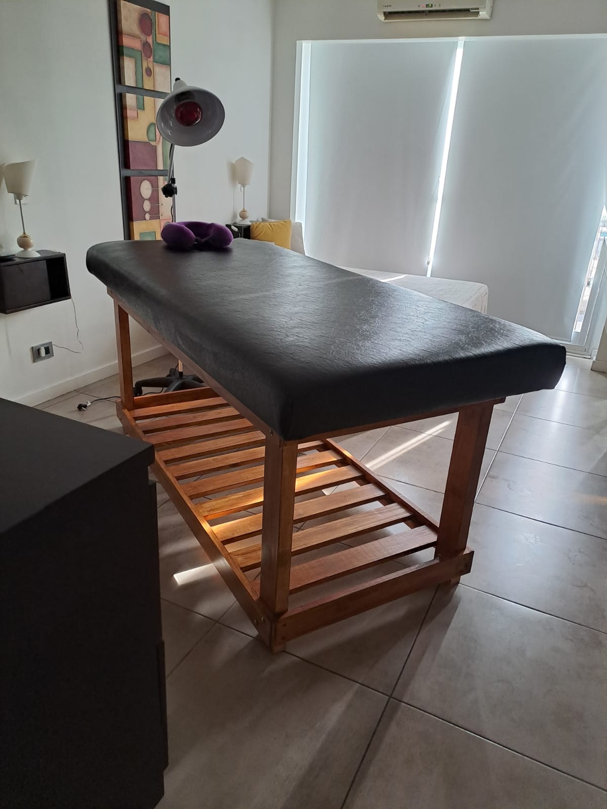 Cabina principal de terapia con camilla de madera, sabanas limpias y luz cálida